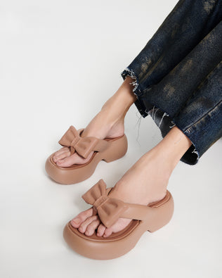 Model's legs wearing a pair of brown Free Fuzzy Platform flip flops