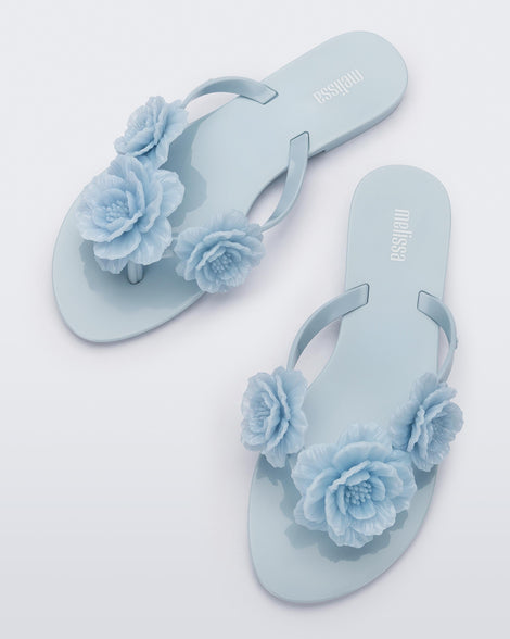 Top view of a pair of blue Harmonic Springtime women's flip flop with 3 blue flowers.