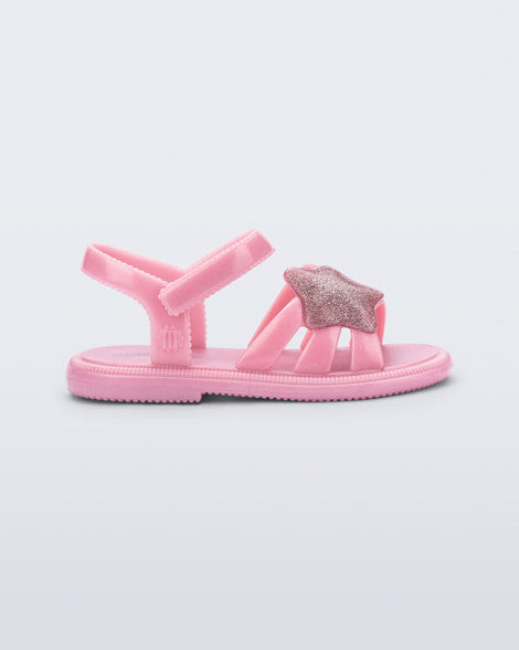 Side view of a pearly pink Hip Sky baby sandal with a glitter pink star on top