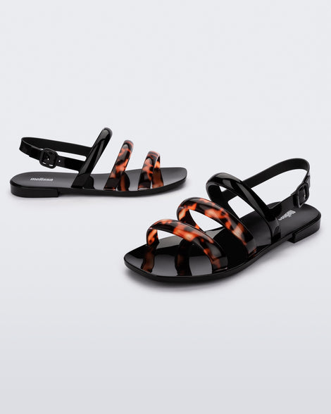Angled view of a pair of black and tortiose Essential Wave women's sandal with adjustable buckle.