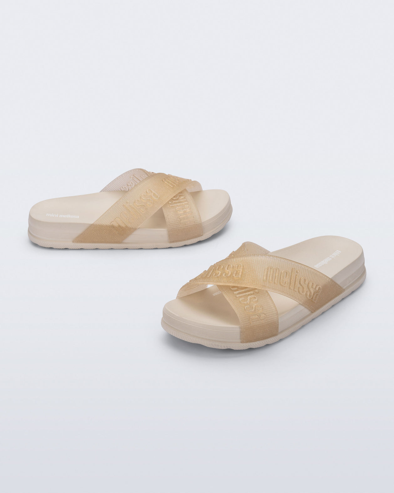 Side and angled view of a pair of beige Cozy M Lover Slides with Melissa on the upper