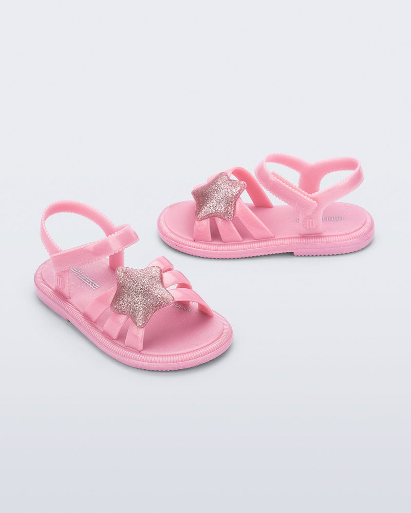 Side and angled view of a pair of pearly pink Hip Sky baby sandals with a glitter pink star on top