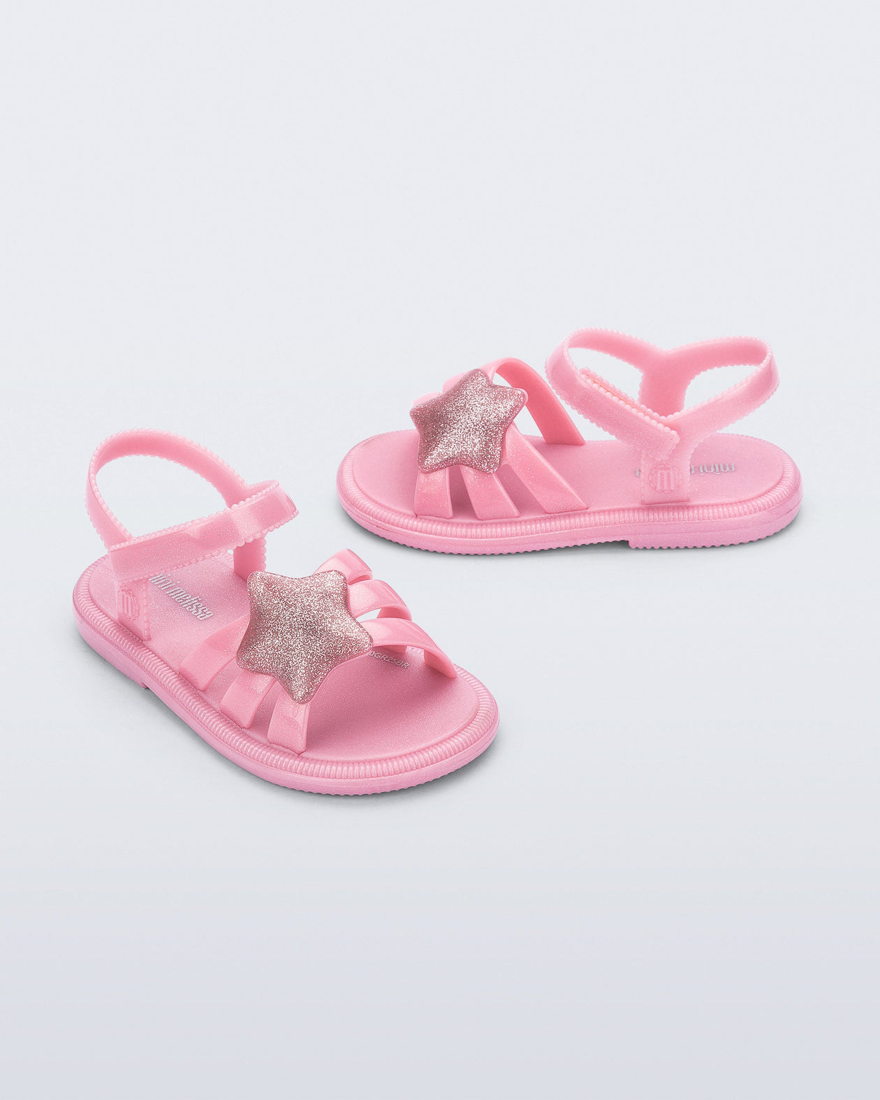 Side and angled view of a pair of pearly pink Hip Sky baby sandals with a glitter pink star on top