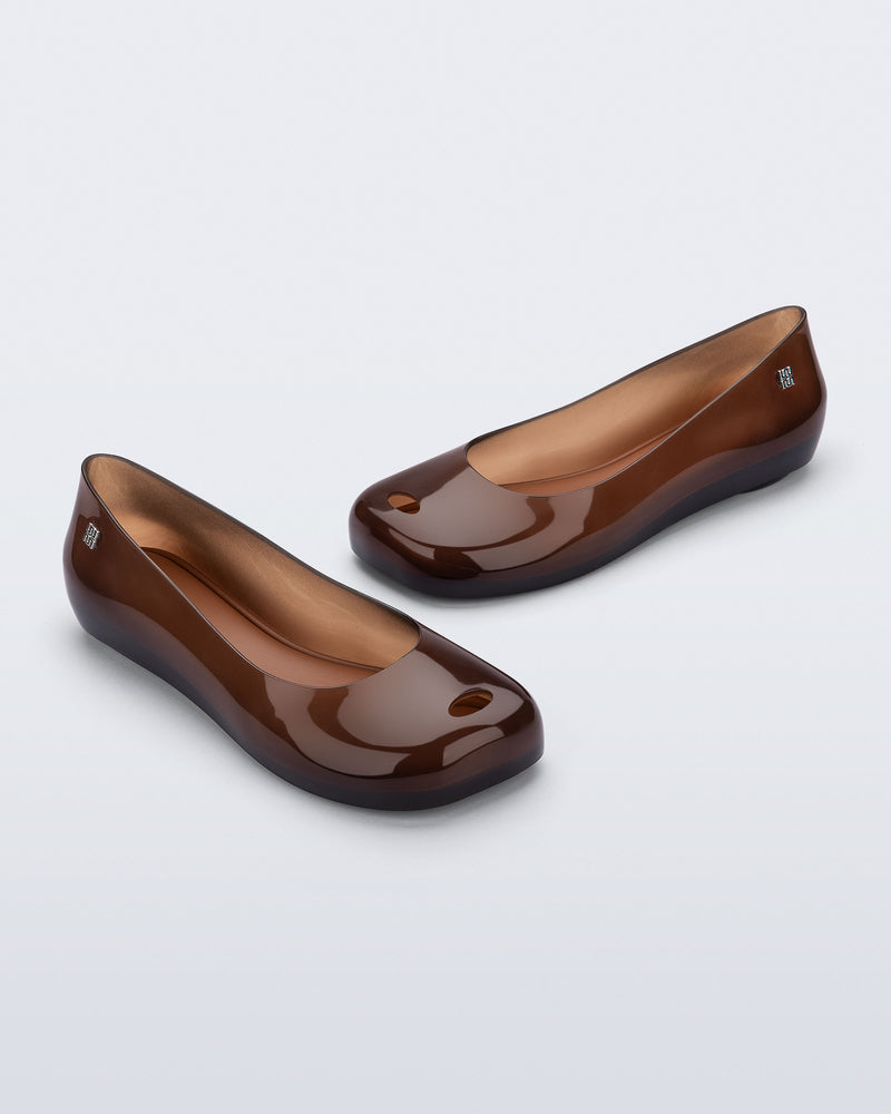 Angled view of a pair of clear brown Ultragirl Futura flats