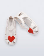 Side and top view of a pair of white Hip Heart Ballerina baby sandals with red heart on front