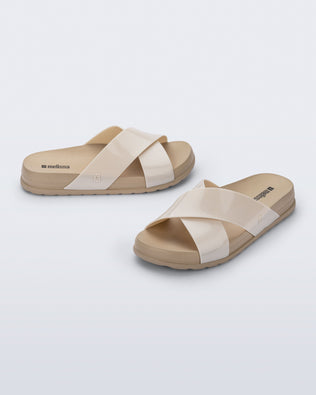 Side and angled view of a pair of beige Cozy Cross sandals with crisscross top straps