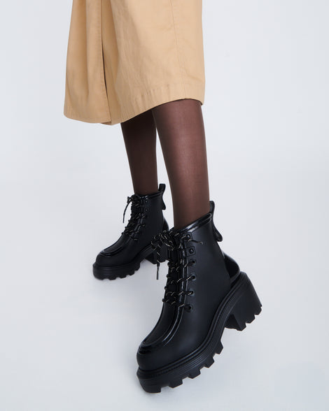 Model's legs wearing a pair of black Track Boot with small heel and black laces