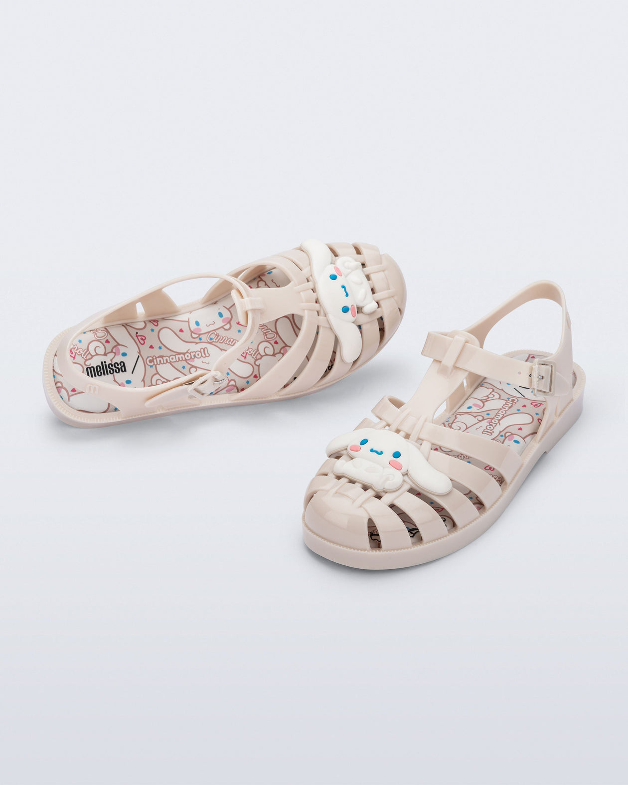 Top and angle view of a pair of beige Possession + Hello Kitty and Friends fisherman sandals with Hello Kitty and friends on the upper