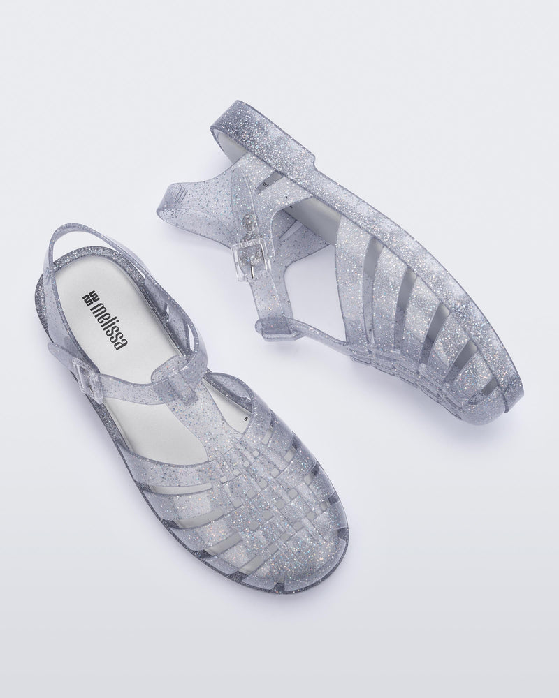 Top and side view of a pair of glitter clear silver Possession fisherman sandals