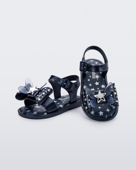 Angled view of a pair of Mini Melissa Mar Sandals with star print for baby in blue with butterfly bow applique and velcro closure on ankle strap.