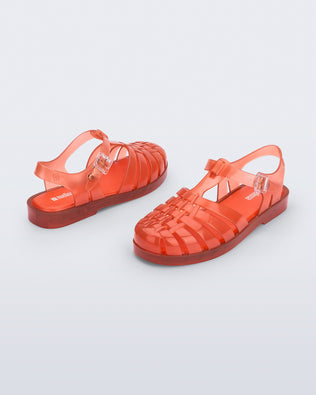 Back and angled view of a pair of transparent orange Possession fisherman sandals
