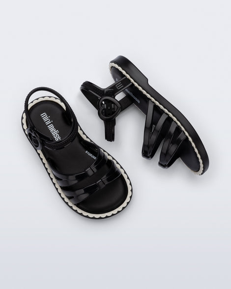 Side and top view of a pair of black Aurora baby sandals with beige trim