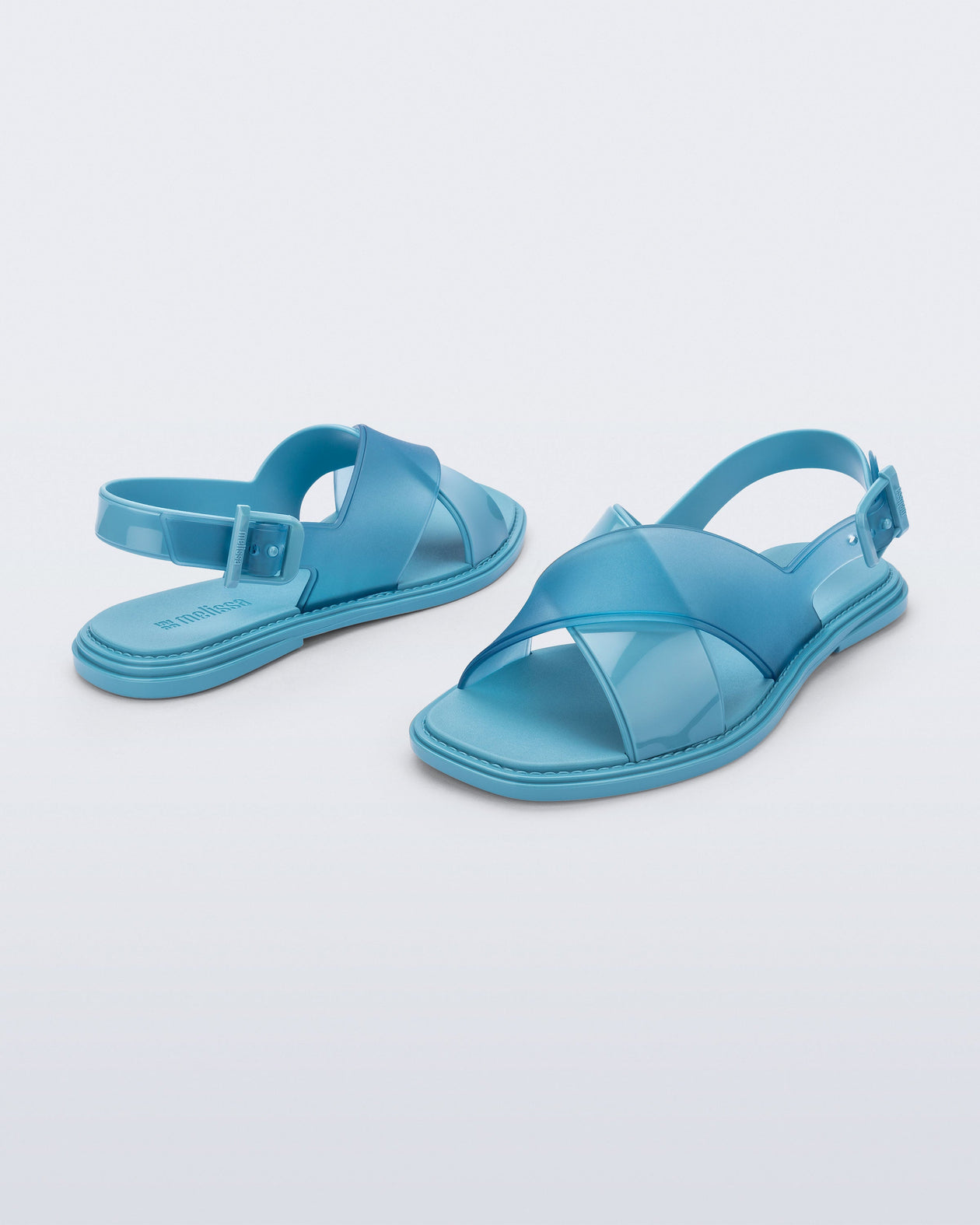 Back and angled view of a pair of blue Cleo sandals with back strap and crisscross top straps