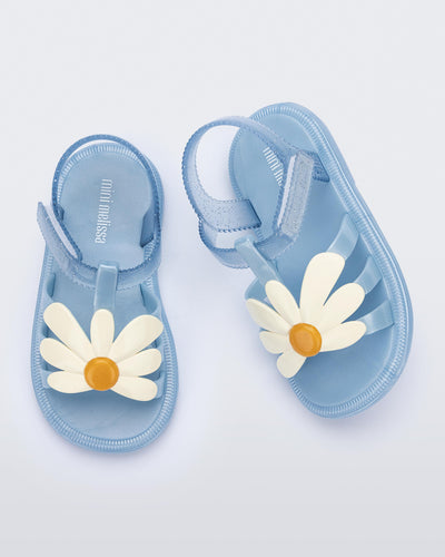 Top view of a pair of metallic blue Hip Bloomy baby sandals with beige daisy on top