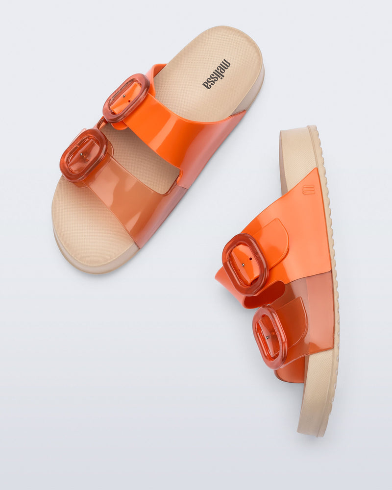 Top and side view of a pair of orange Cozy slides with beige soles