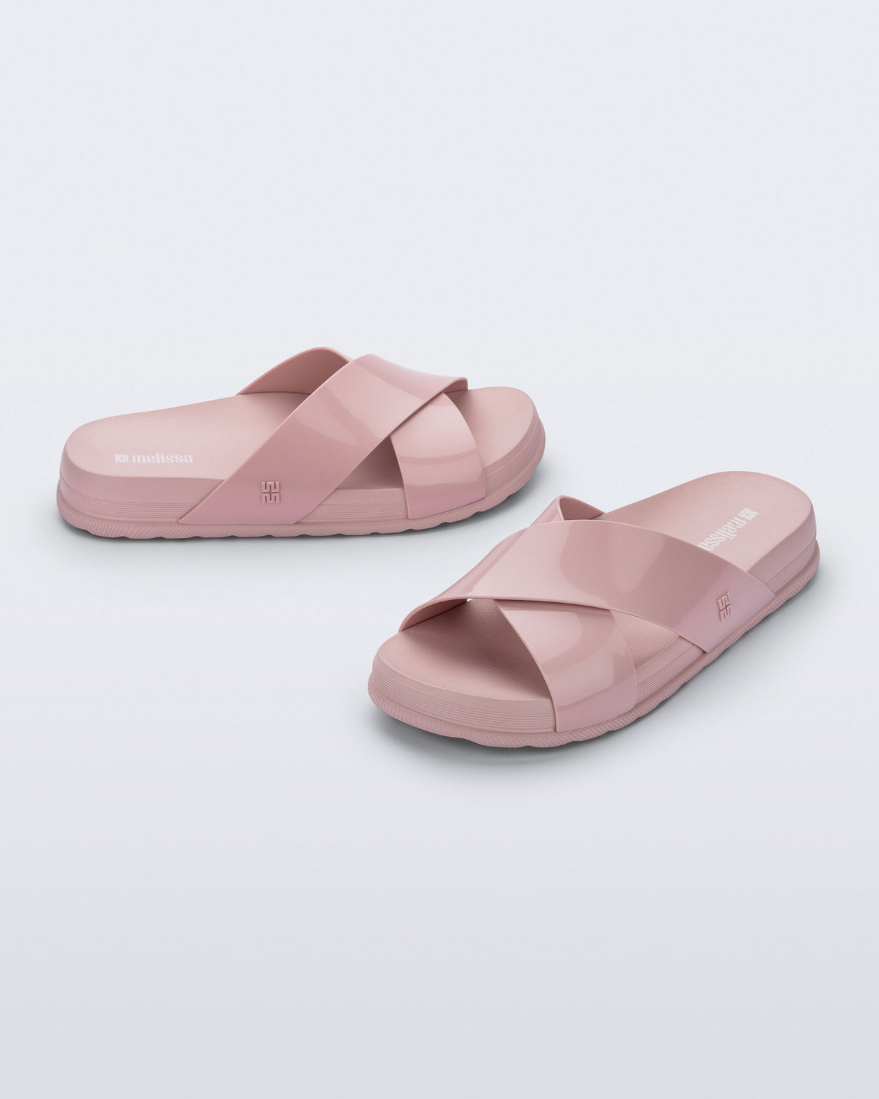 Side and angled view of a pair of pink Cozy Cross sandals with crisscross top straps