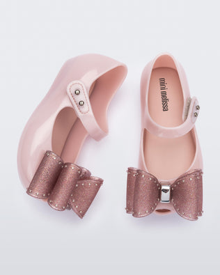 Top and side view of a pair of light pink Ultragirl Classic bow baby flats with glitter pink bow