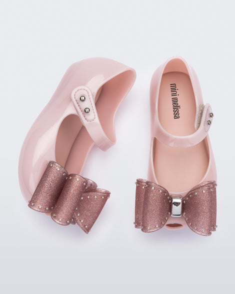 Top and side view of a pair of light pink Ultragirl Classic bow baby flats with glitter pink bow