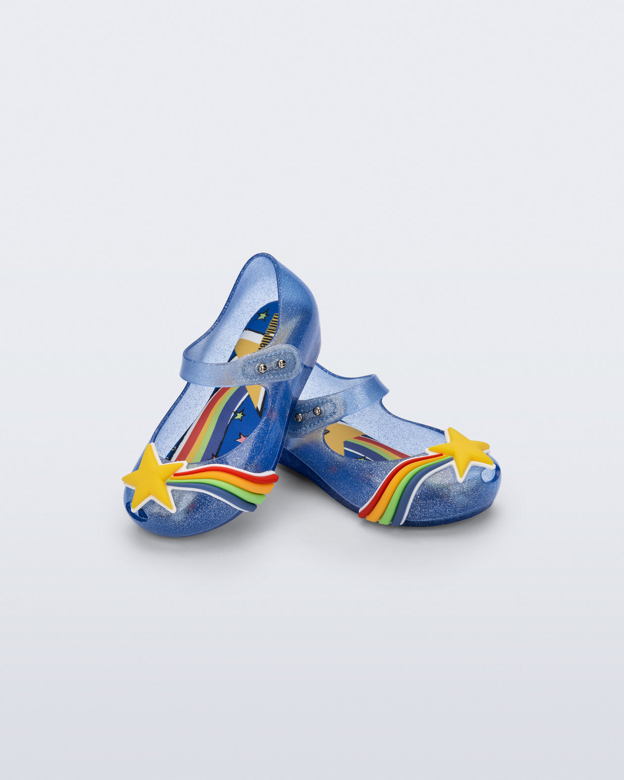 Angled view of a pair of glitter blue Ultragirl Colors baby flats with yellow star and rainbow on top