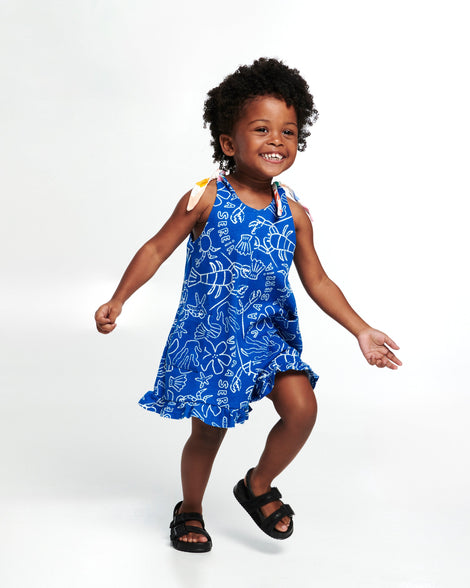Child model in a blue dress wearing a pair of black Cozy M Lover sandals