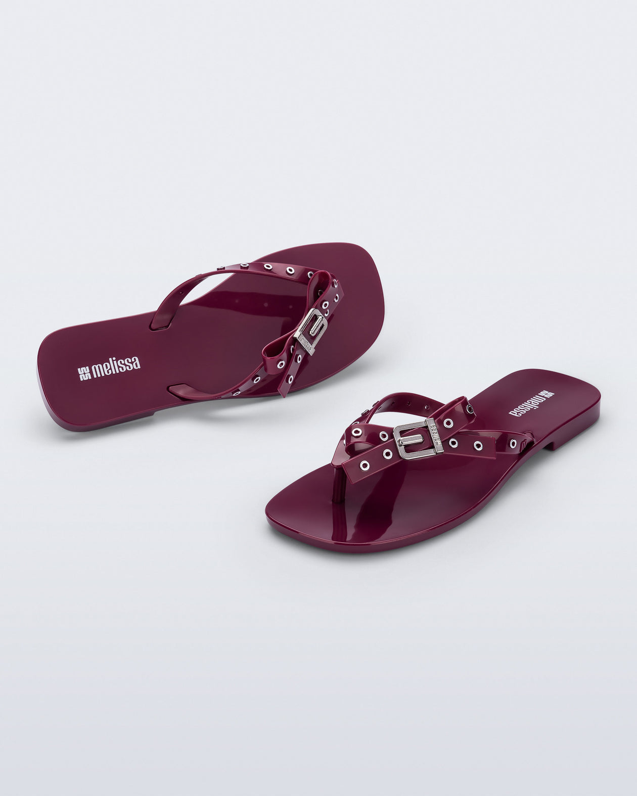 Side and angled view of a pair of red Harmonic Squared flip flops with bow on strap