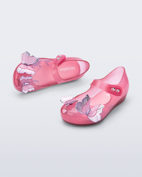 Top and angled view of a pair of pink glitter Ultragirl Butterfly baby flats with pink butterflies on top