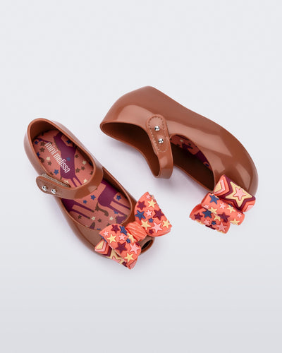 Top and side view of a pair of brown with orange star patterned bow Ultragirl Wonderland baby flats
