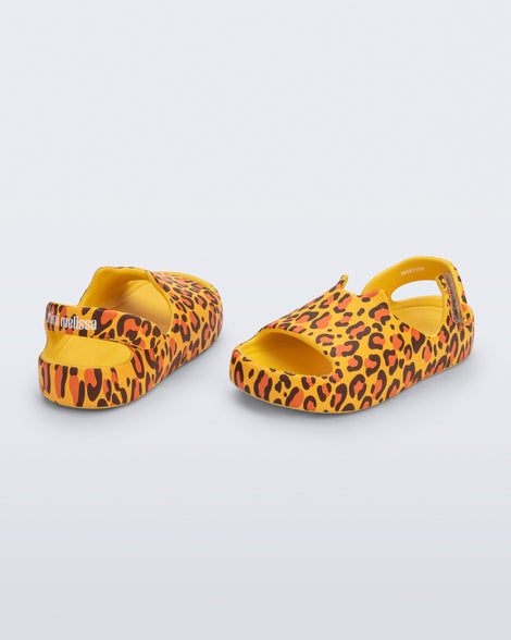 Back and angled view of a pair of yellow Free Cute baby sandals with leopard print