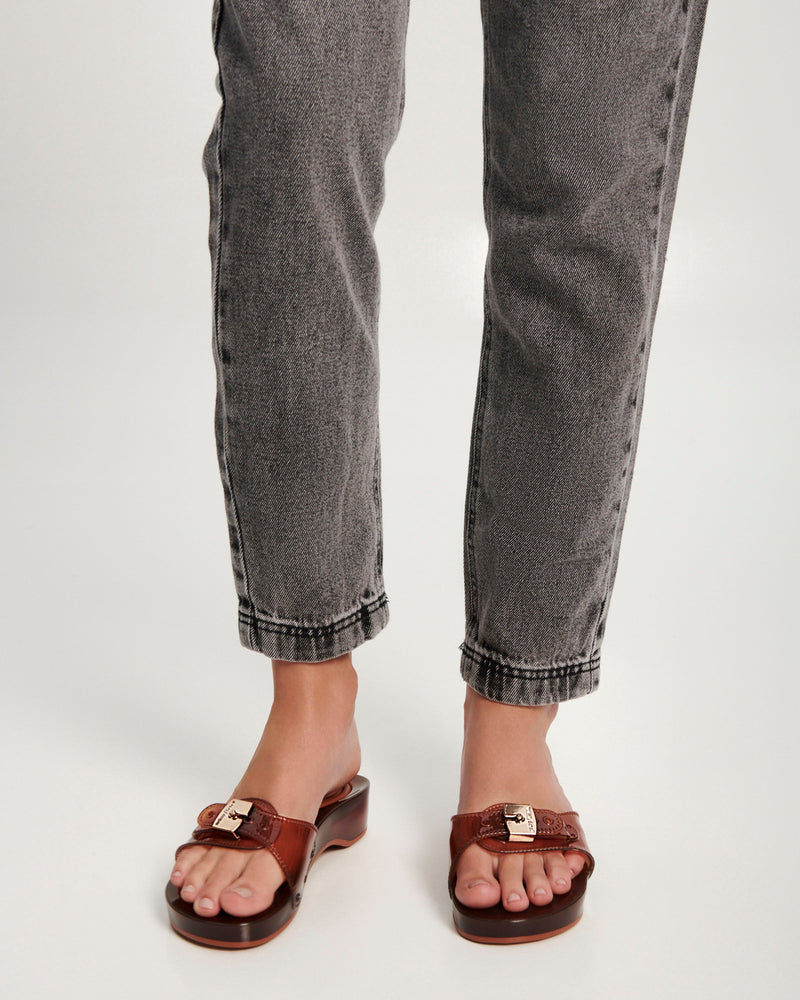 Model's legs wearing a pair of clear brown Pescura Heel + Scholl slides with top buckle