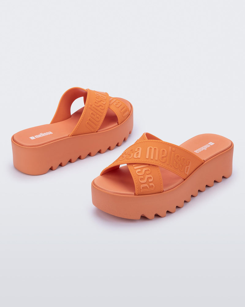 Back and side view of a pair of beige M Lover Cross Strap platform slides