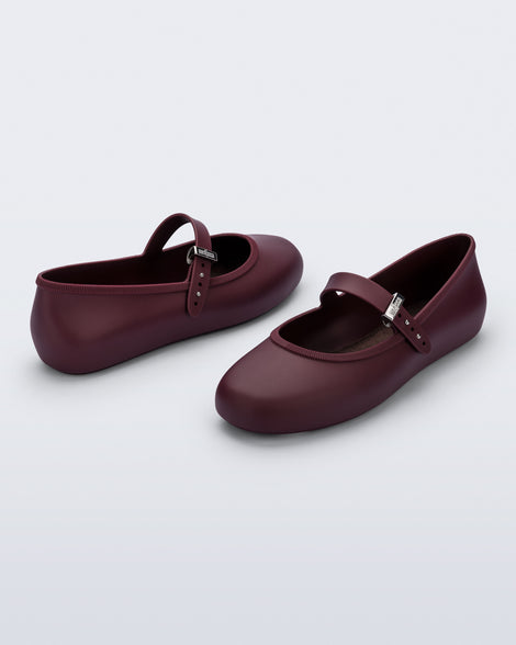 Back and angled view of a pair of burgundy Soft Ballerina flats with top strap and silver buckle