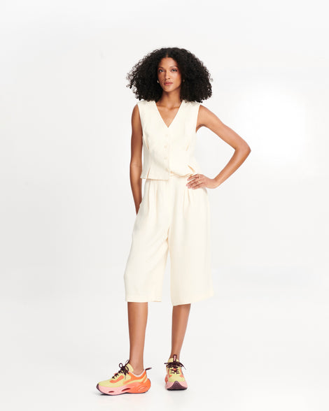 Model in a white outfit wearing a pair of orange/green/pink X Loop sneakers