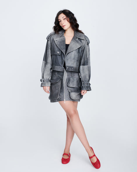 Model in a grey short trench coat wearing a pair of red Soft Ballerina Delicate Bow flats with top strap and bow