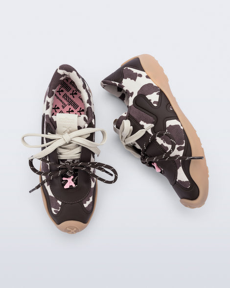 Top and side view of a pair of black and white cow print X Bend sneakers with beige sole