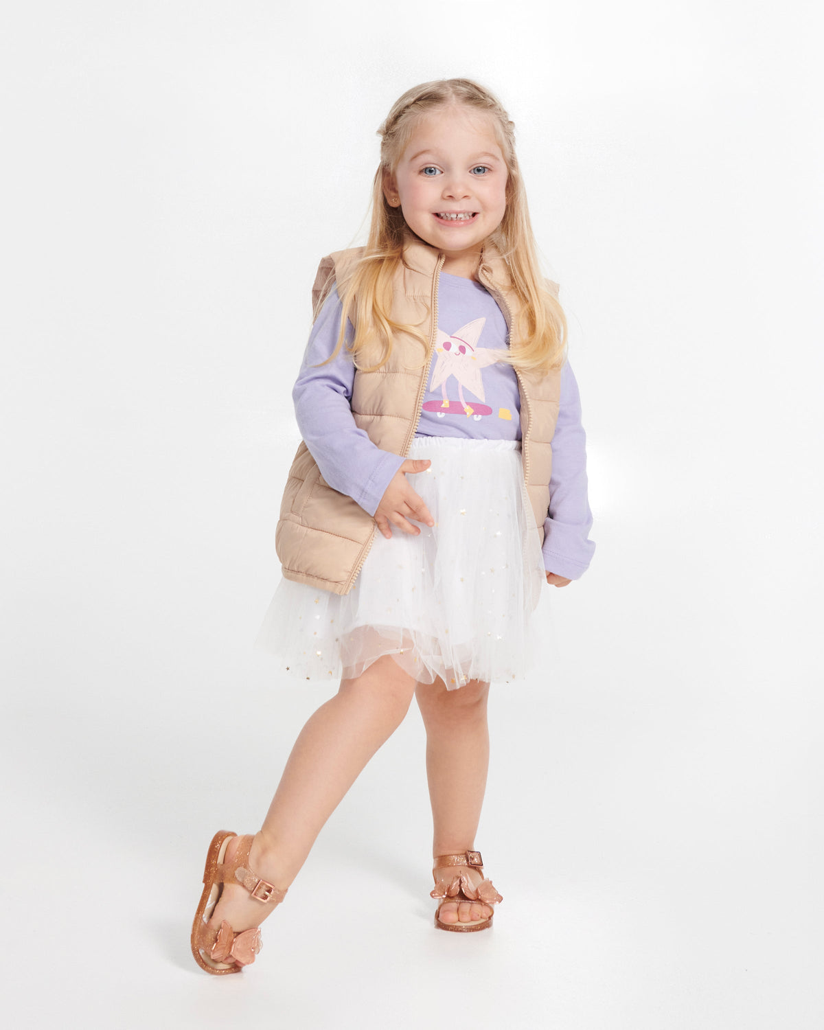 Child model in a white skirt and purple top wearing a pair of glitter beige baby Butterfly sandals with butterflies