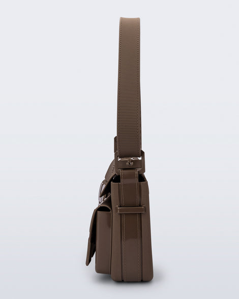 Side view of a brown Cargo bag with two small pockets on the front and an adjustable strap