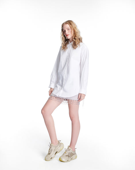 Model in a white outfit wearing a pair of beige X Loop sneakers