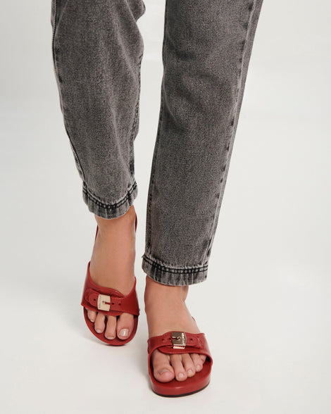 Model's legs wearing a pair of red Pescura Heel + Scholl slides with top buckle
