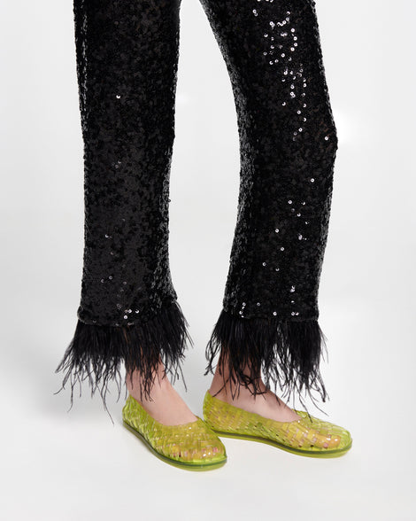 Model's legs in black pants wearing a pair of clear green Possession Ballerina flats