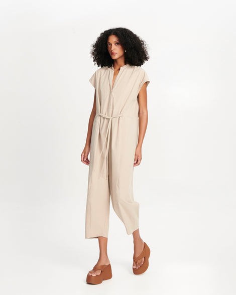 Model in a tan one piece outfit wearing a pair of brown Free Thong Wedge platform flip flop sandals