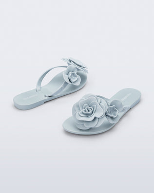 Back and angled view of a pair of blue Harmonic Petals kids flip flops with flowers
