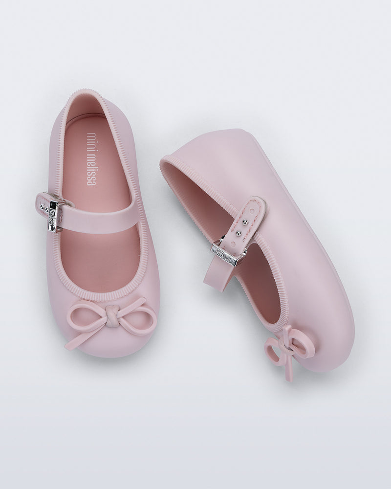 Side and top view of a pair of pink Soft Ballerina Delicate Bow baby flats with top strap and bow