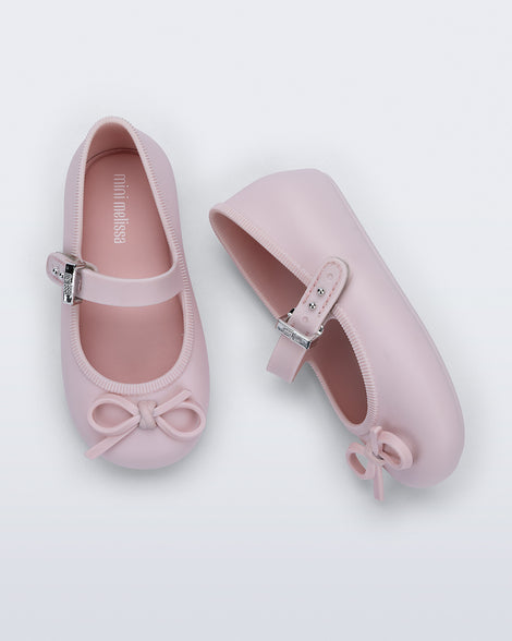 Side and top view of a pair of pink Soft Ballerina Delicate Bow baby flats with top strap and bow