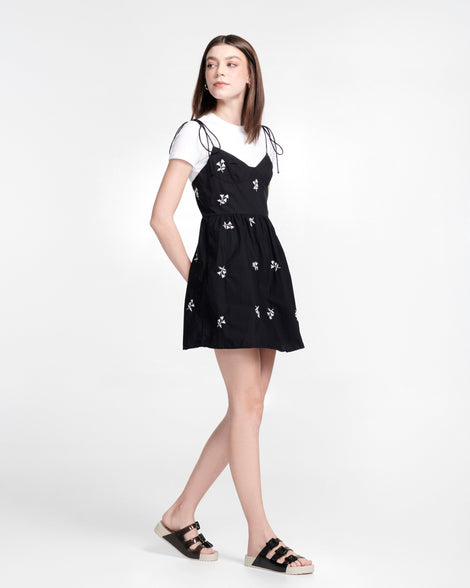 Model in a black dress wearing a pair of beige Cozy Stripes sandals with black upper with 3 buckles