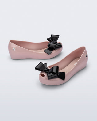 Top and side angled view of a pair of pink Ultragirl Classy kids ballerina flats with black bow