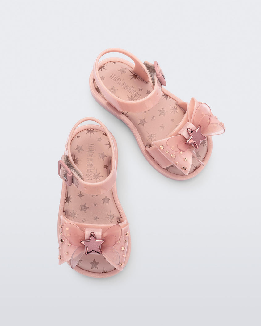 Overhead view of a pair of Mini Melissa Mar Sandals with star print for baby in pink with butterfly bow applique and velcro closure on ankle strap.