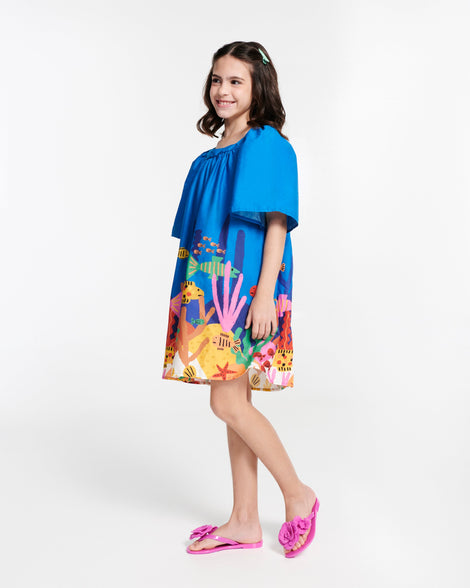 Child model in a blue dress wearing a pair of pink Harmonic Petals kids flip flops with flowers