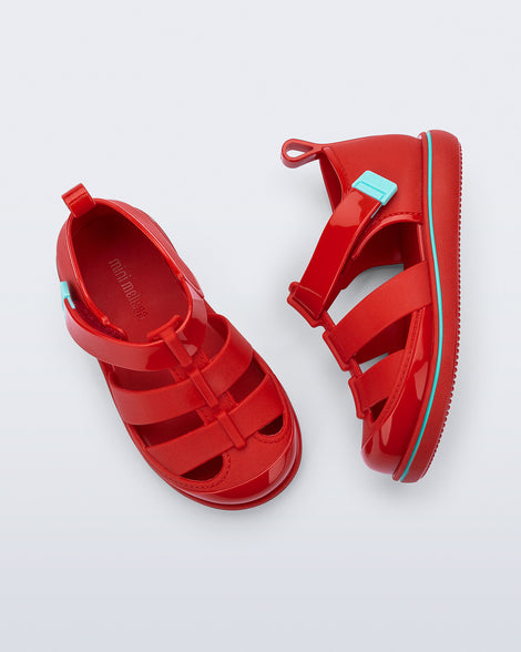 Top and side view of a pair of red Smash closed toe baby sandals with blue trim