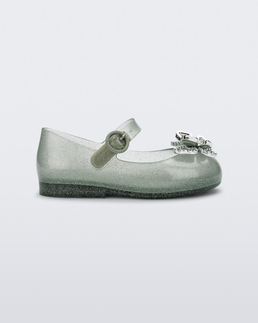 Side view of a glitter green Mini Melissa Sweet Love Butterfly flat with a top strap and a silver butterfly detail on the toe