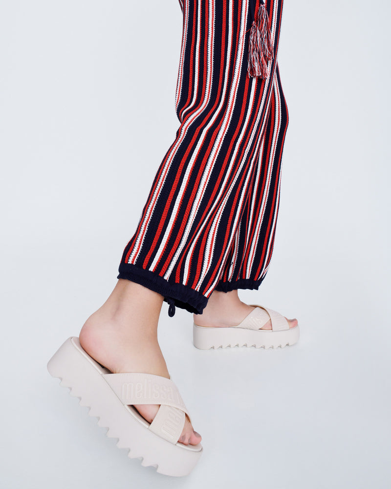 Model's legs wearing a pair of beige M Lover Cross Strap platform slides
